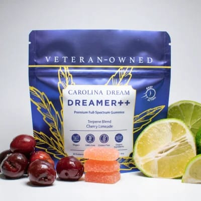 A pouch of Carolina Dream Dreamer++ gummies surrounded by fresh cherries and limes.