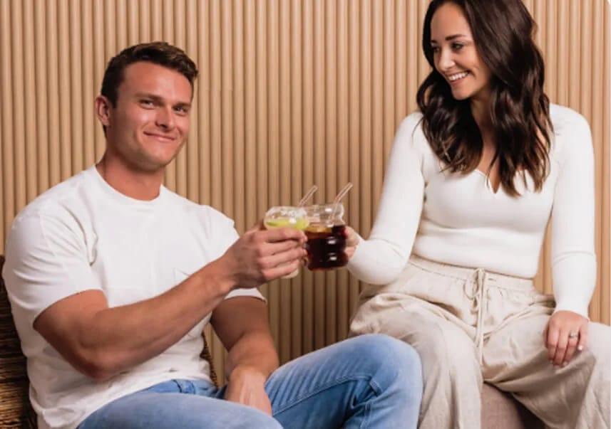 Dylan and Sammi Dreiling, co-founders of Ananda Elixirs, smiling and clinking glasses