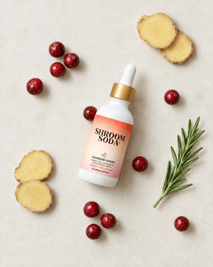 Shroom Soda bottle surrounded by cranberries, ginger slices, and a sprig of rosemary.