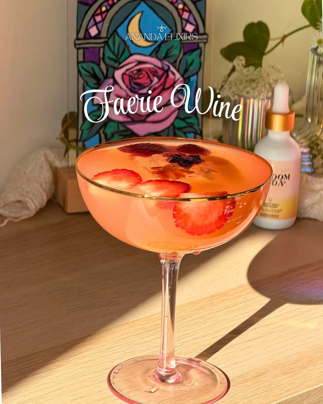 A peach-pink drink in a gold-rimmed coupe glass, filled with ice, strawberry slices and edible flowers, with a Shroom Soda dropper bottle and a stained-glass rose panel behind it.