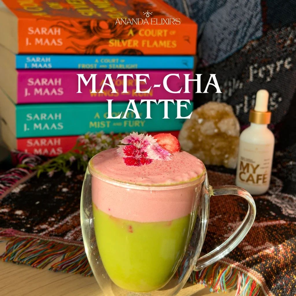 A glass mug of layered green matcha and pink latte topped with flowers and strawberry.