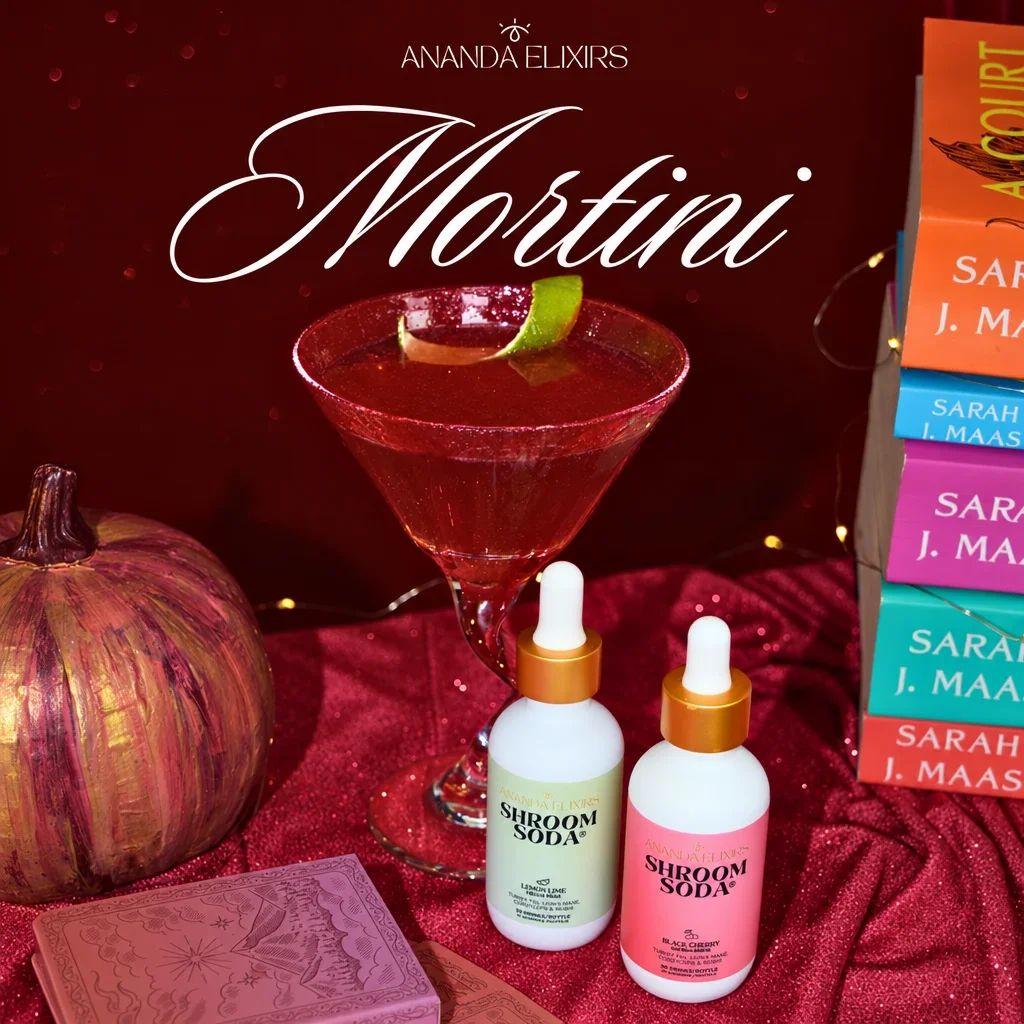 A red cocktail in a martini glass, two Shroom Soda bottles, and a painted pumpkin.