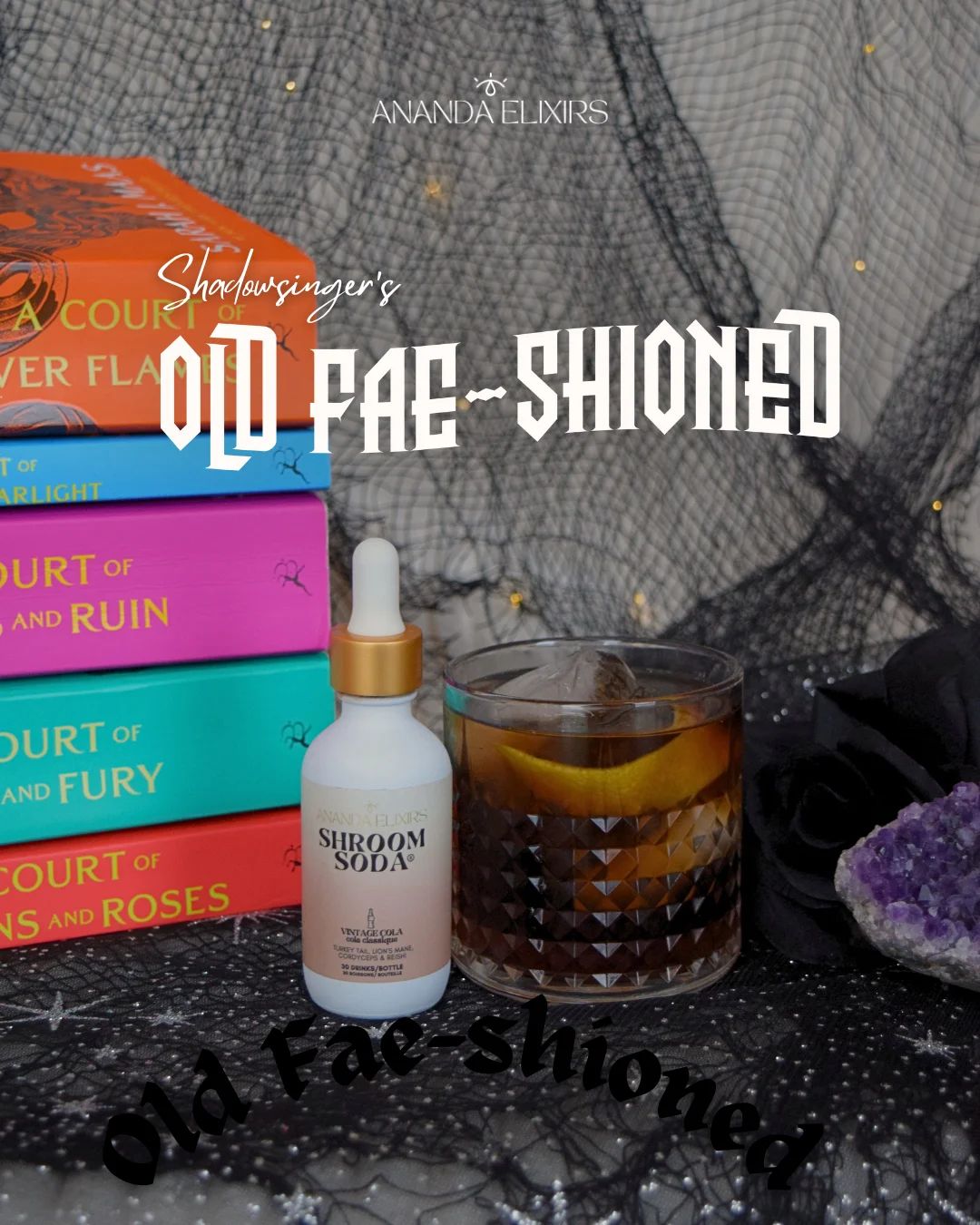 A Shroom Soda bottle, a cocktail, colorful books, and an amethyst crystal on black fabric.