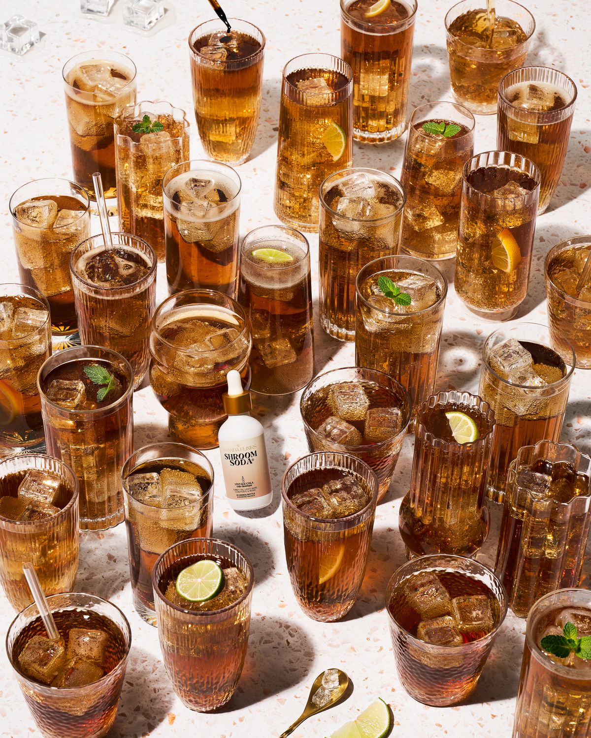 Dozens of iced Shroom Soda drinks with lime and mint around one small bottle